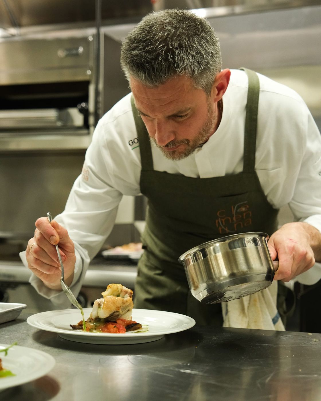 Chef Michele Rocchi finishing a plate on the pass in the Clementina kitchen