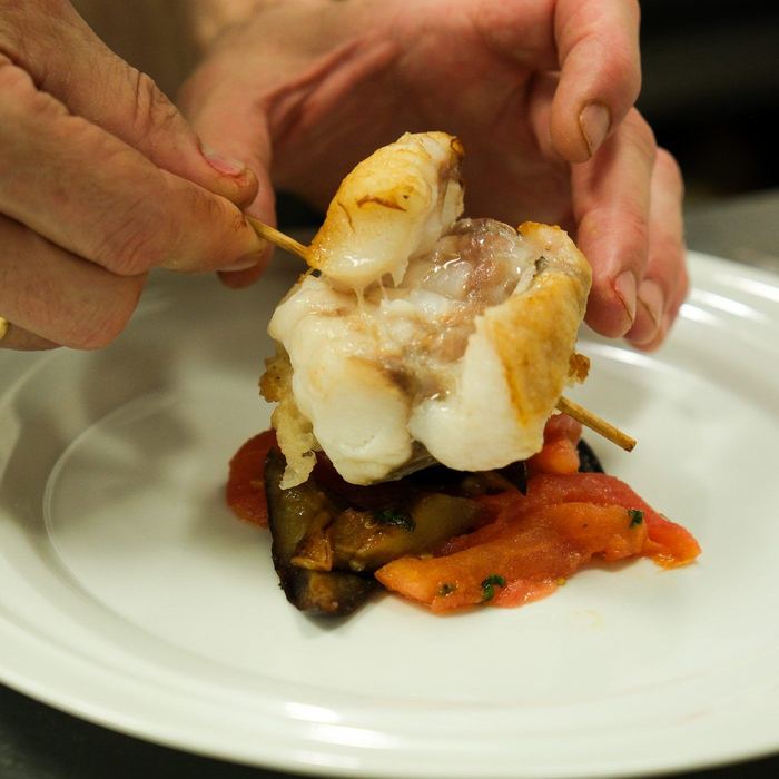 Monkfish on a skewer set over stewed peppers and eggplant