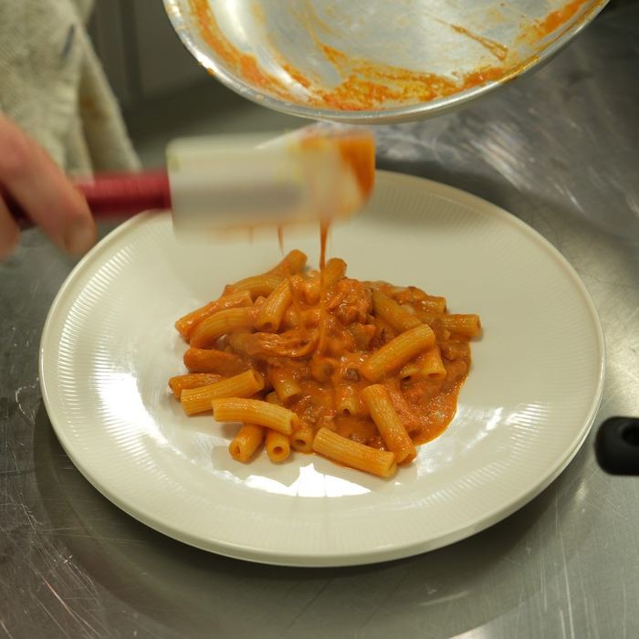Pasta in tomato sauce being plated straight from the pan