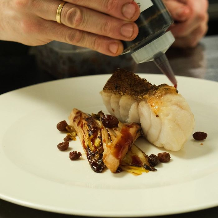 Scallops with charred onion and raisins, finished with a grating of citrus