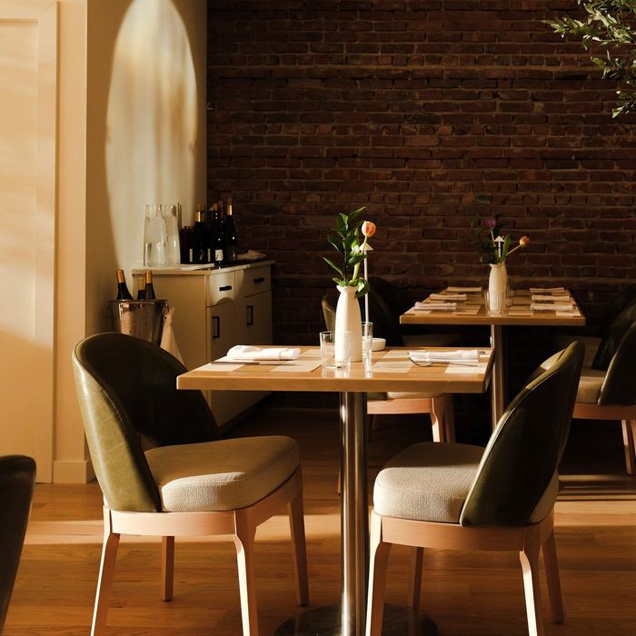 Tables set for dinner at Clementina against exposed brick and warm wood