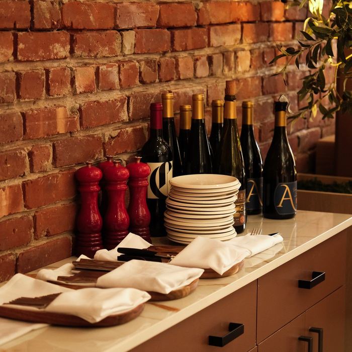 Italian wine bottles and stacked plates on the service station at Clementina