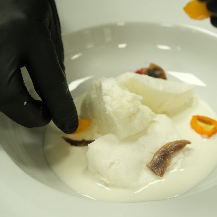 A white fish crudo plated with citrus, finished by hand